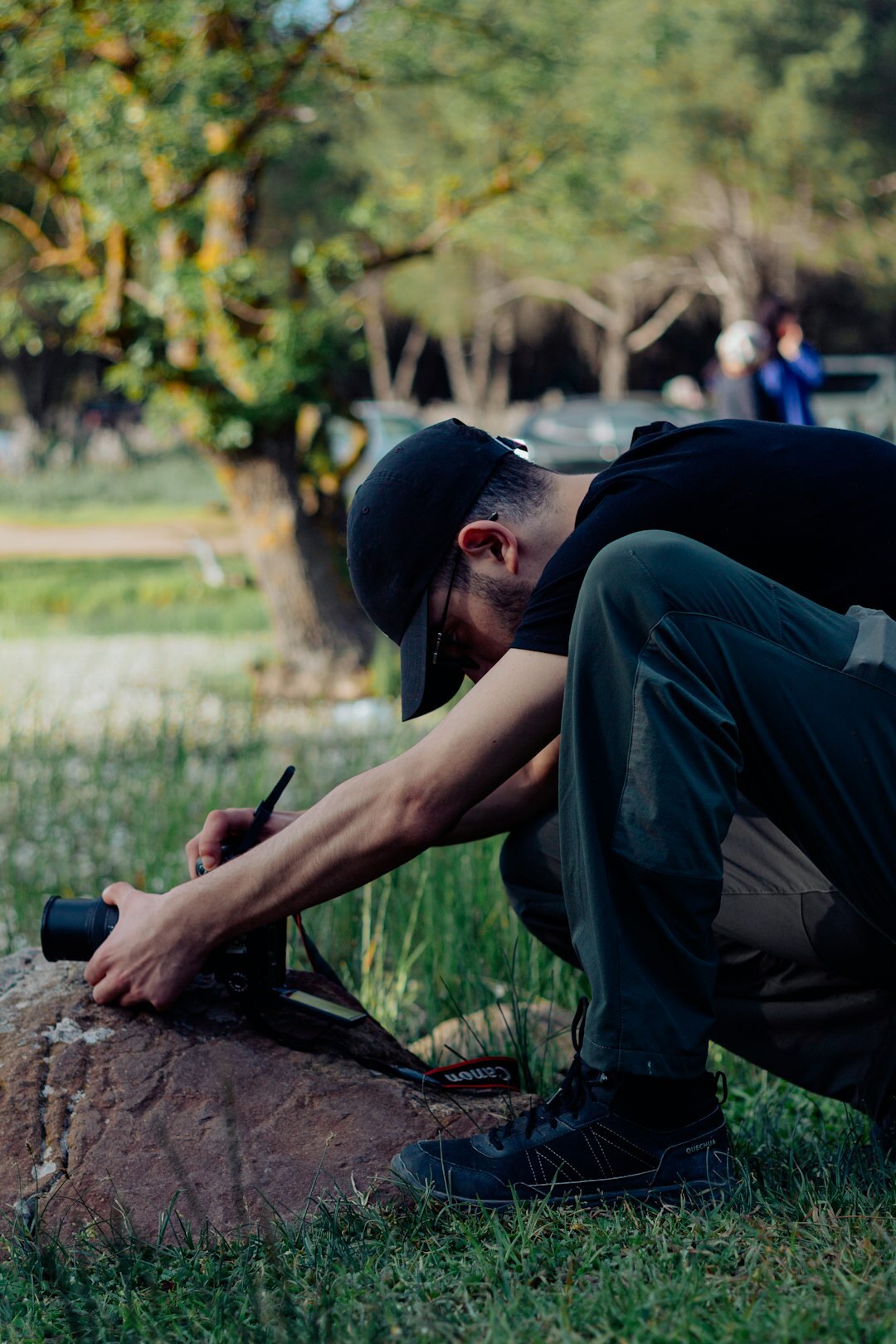 Photographer crouching to photograph a subject outdoors